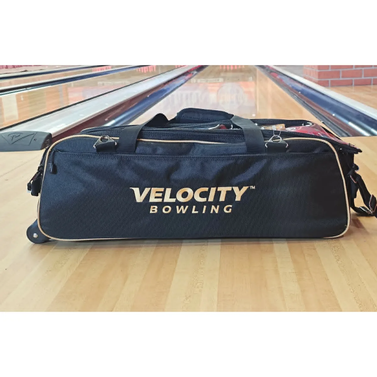 Velocity 3 Ball Triple Tote Black Gold bowling bag on the approach at a BowlersMart pro shop lane